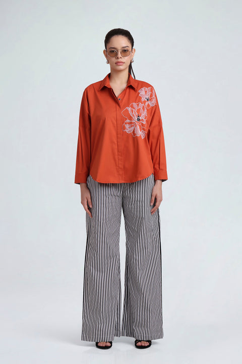 Eden rust-orange cotton shirt, full-length front view with striped trousers