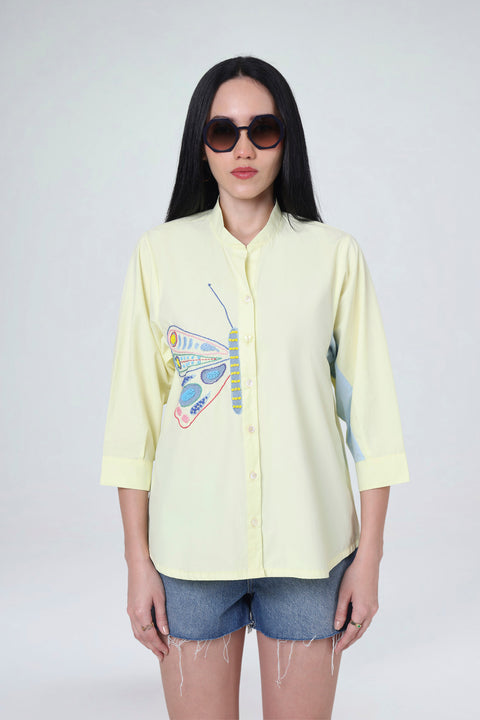Elvie pale yellow cotton shirt for women with butterfly embroidery and a blue contrast sleeve panel, front view